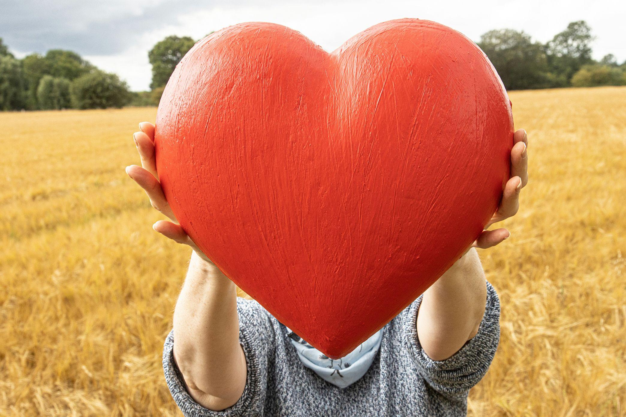 Someone holding an outstretched heart in a field