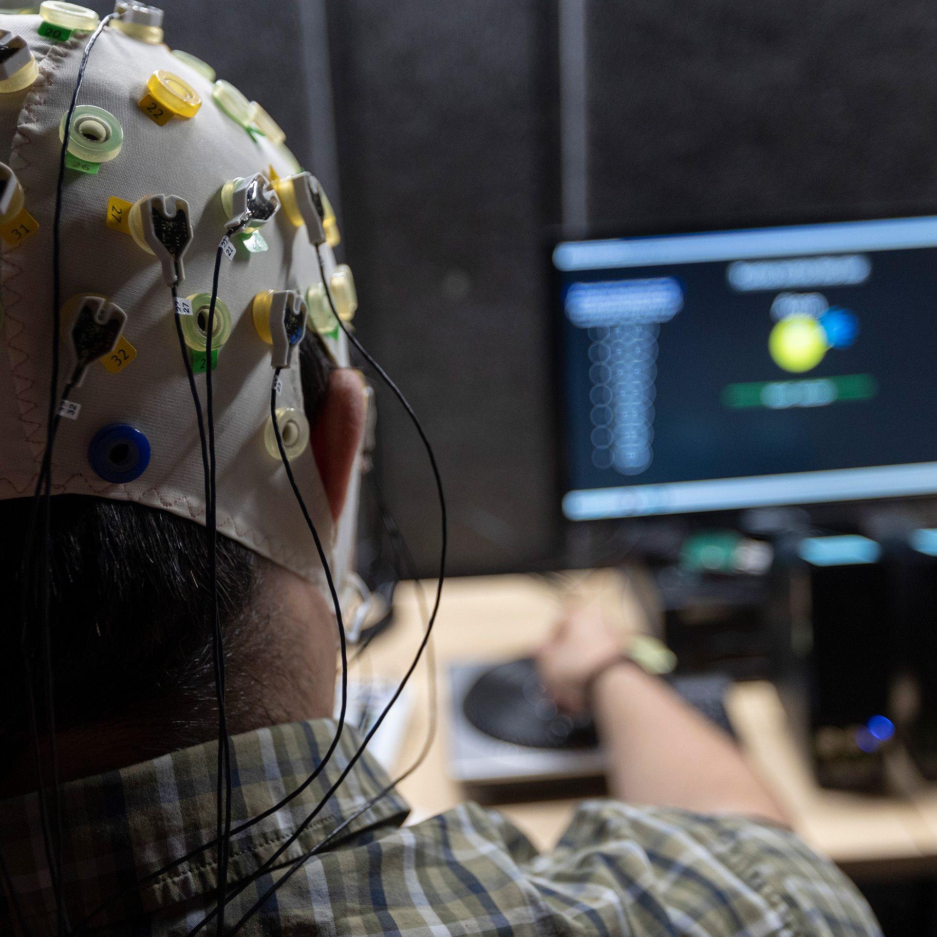 Person with EEG cap turning a music box